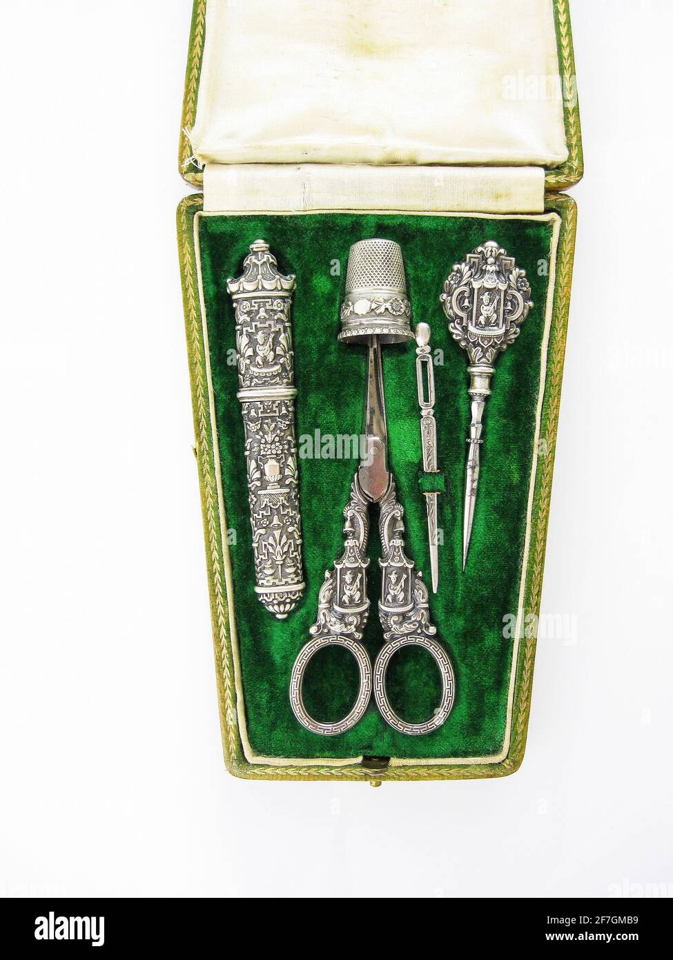 Antique silver French sewing kit in a velvet lined etui or box with scissors, needle, needle case, picker and thimble. Ornate design of man playing ma Stock Photo
