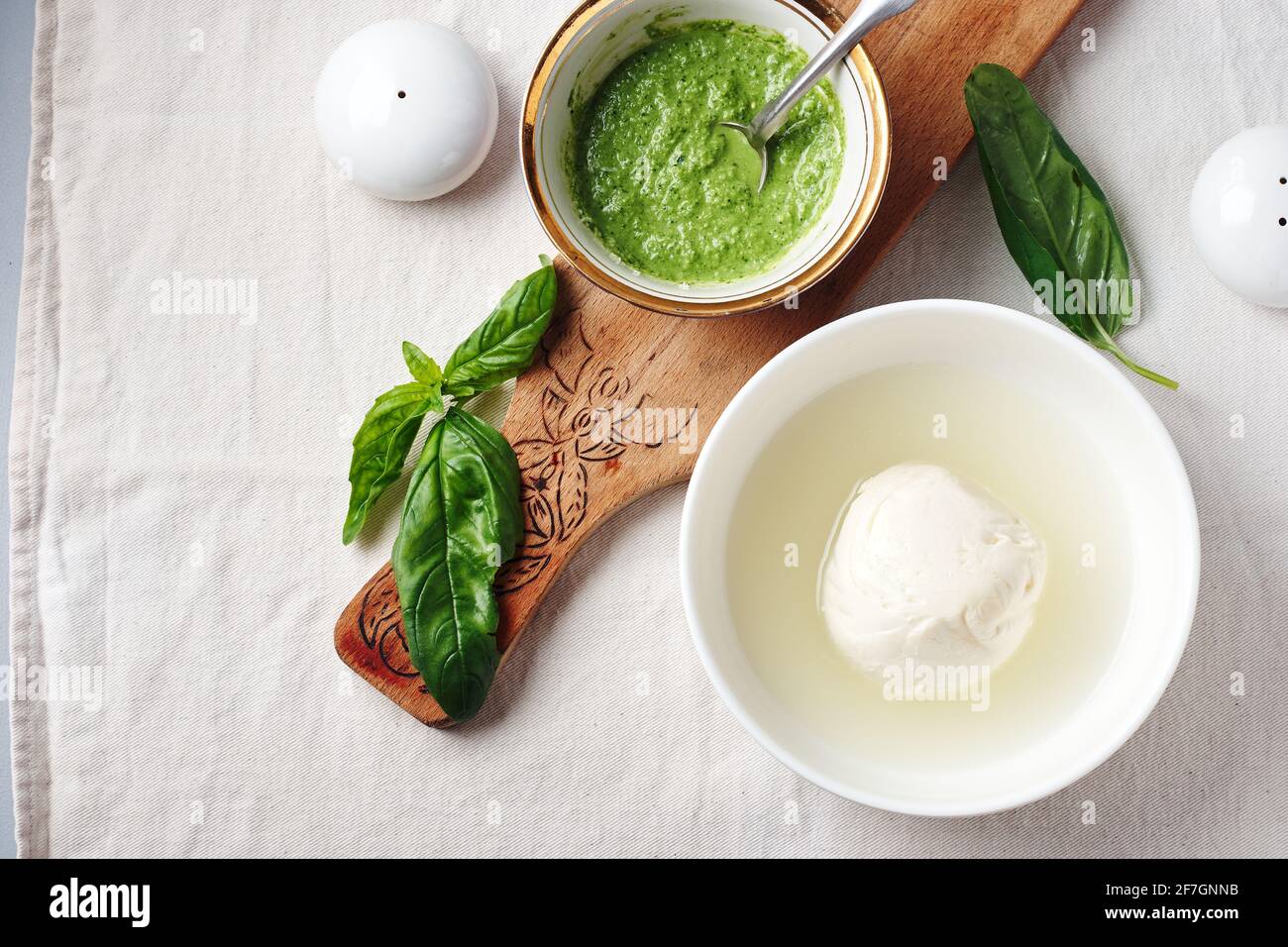 Mozzarella cheese ball in a bowl, pesto sauce and fresh basil leaves. Stock Photo