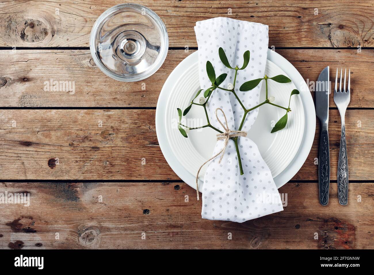 Table setting. White plates, cutlery, napkin and mistletoe Stock Photo