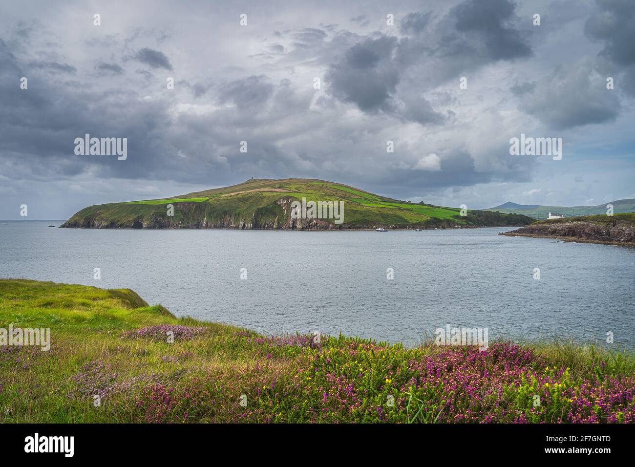 Tour boats with tourists looking for local attraction, Fungie dolphin. Dingle lighthouse on the cliffs with dramatic storm clouds, Kerry, Ireland Stock Photo