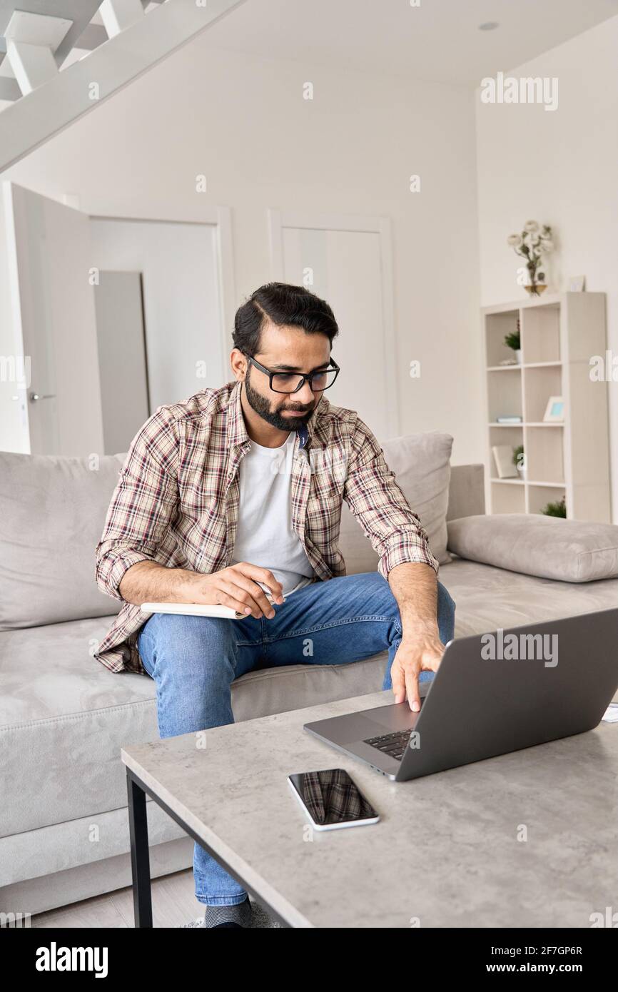 Indian man working or learning online from home office using laptop