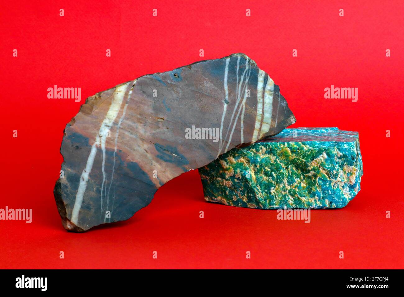 Two pieces of natural raw minerals, amazonite and jasper, against bright red background Stock Photo