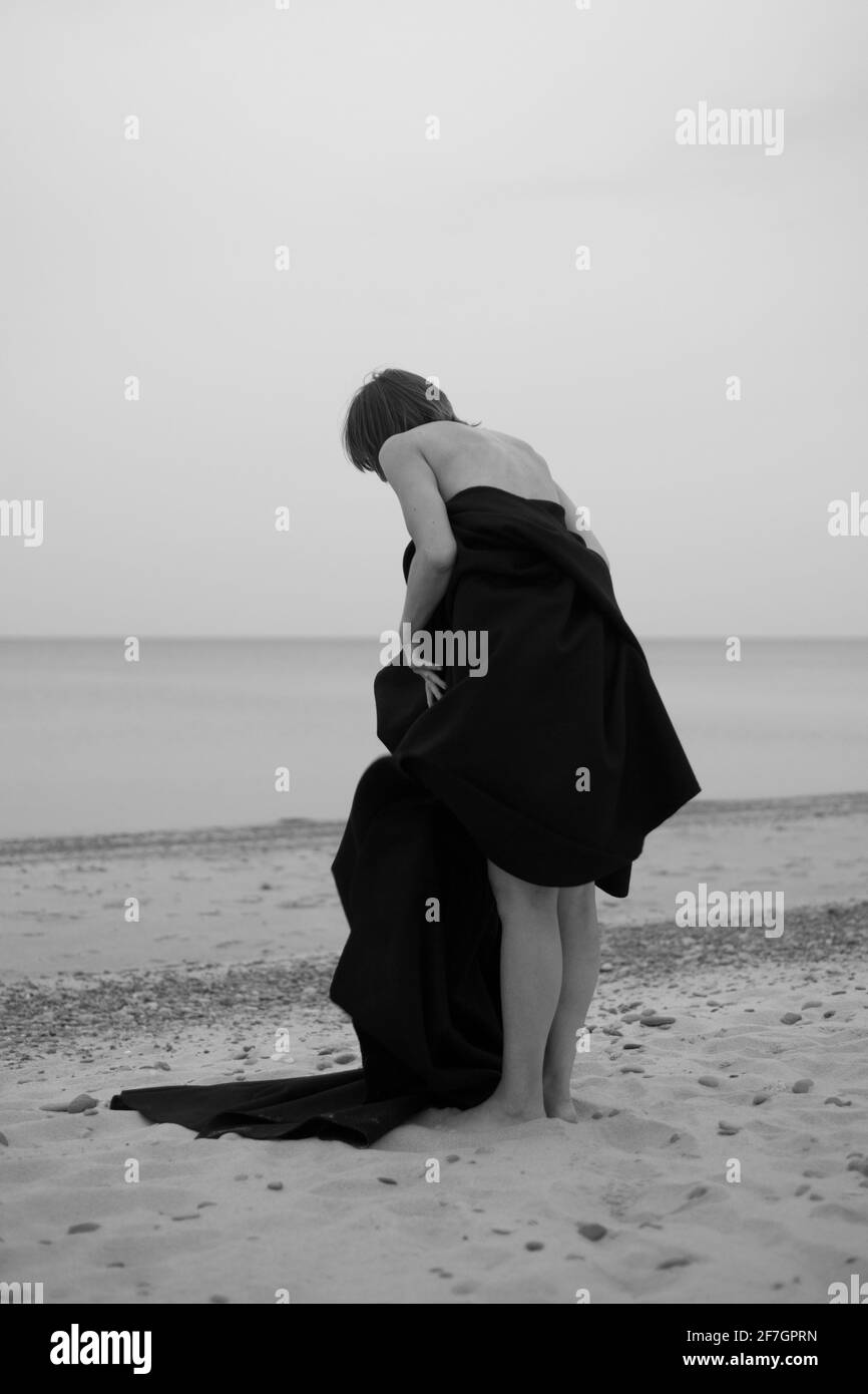 Woman in black dress stands on the beach, black and white photo Stock ...