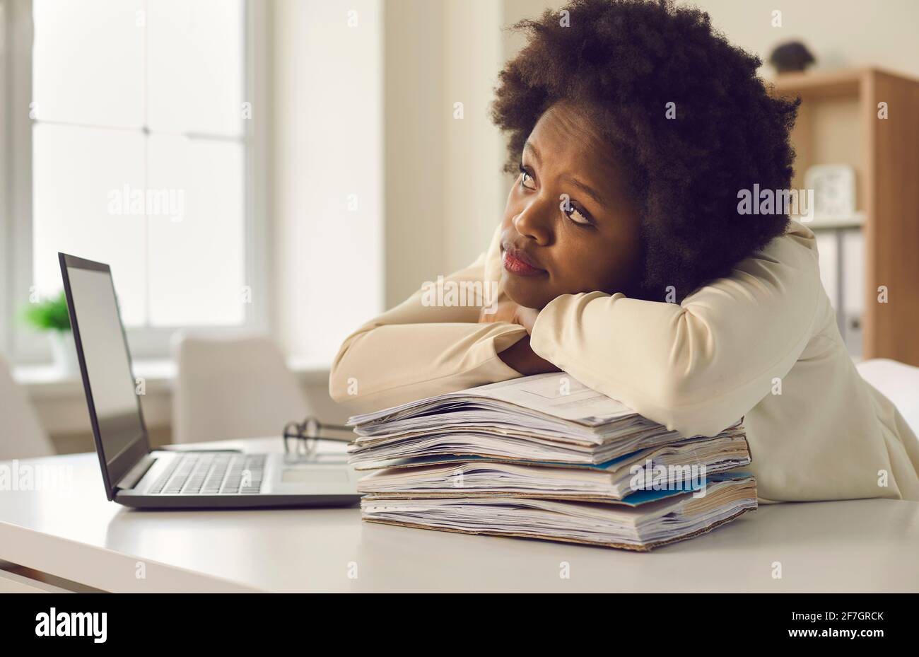 Young african american office worker dreaming leaning head on paper stack Stock Photo