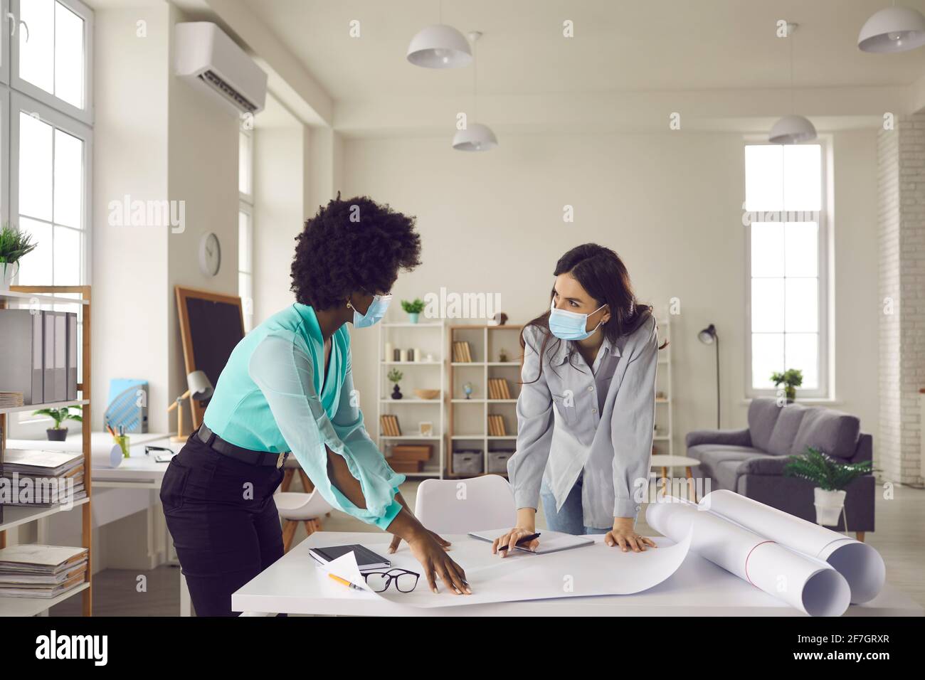 Two creative women wearing face masks working on design project in