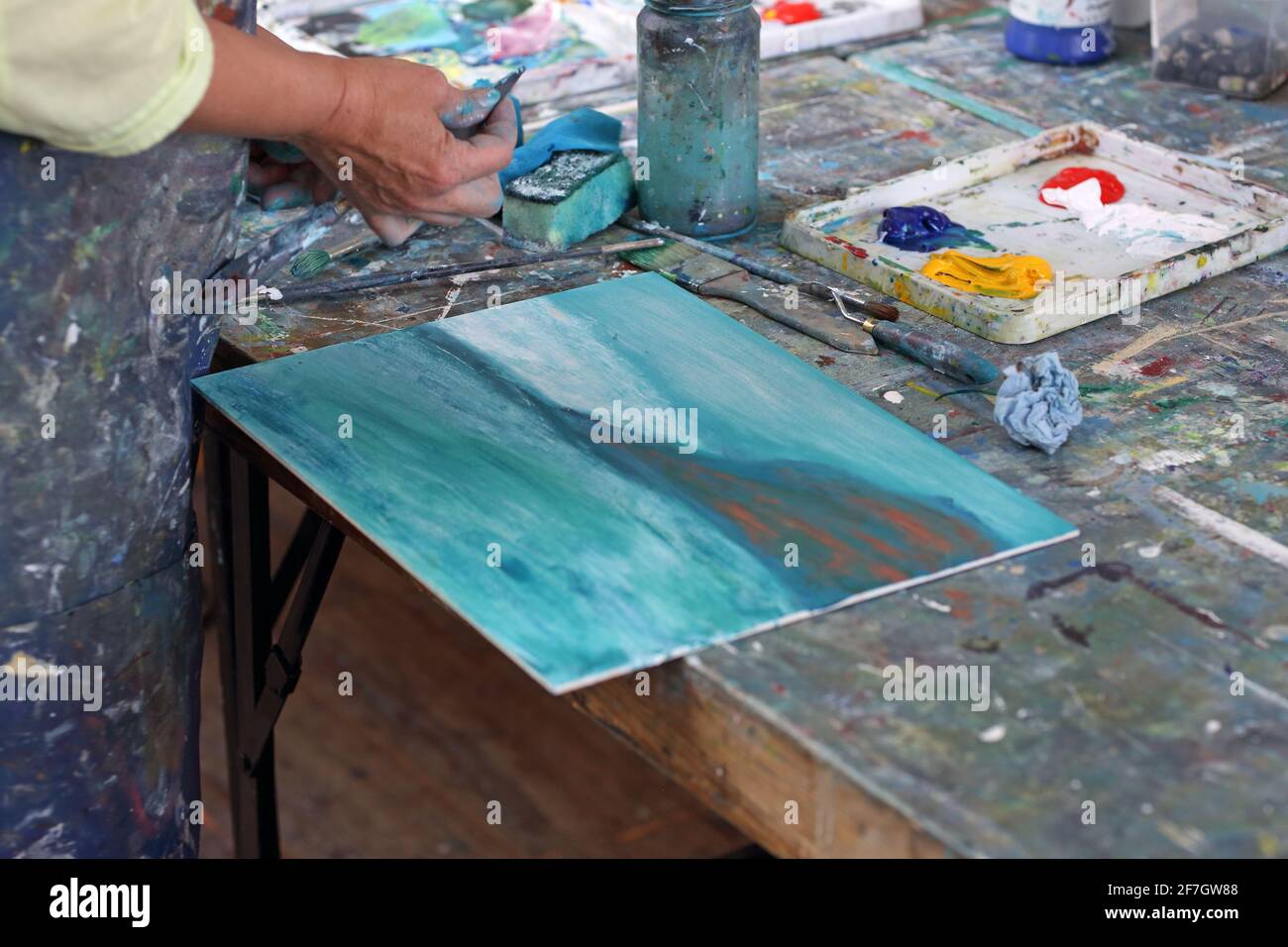 Unrecognizable woman works on a painting. She is using a spong as she paints on a canvas in St Ives ,Cornwall ,England Stock Photo