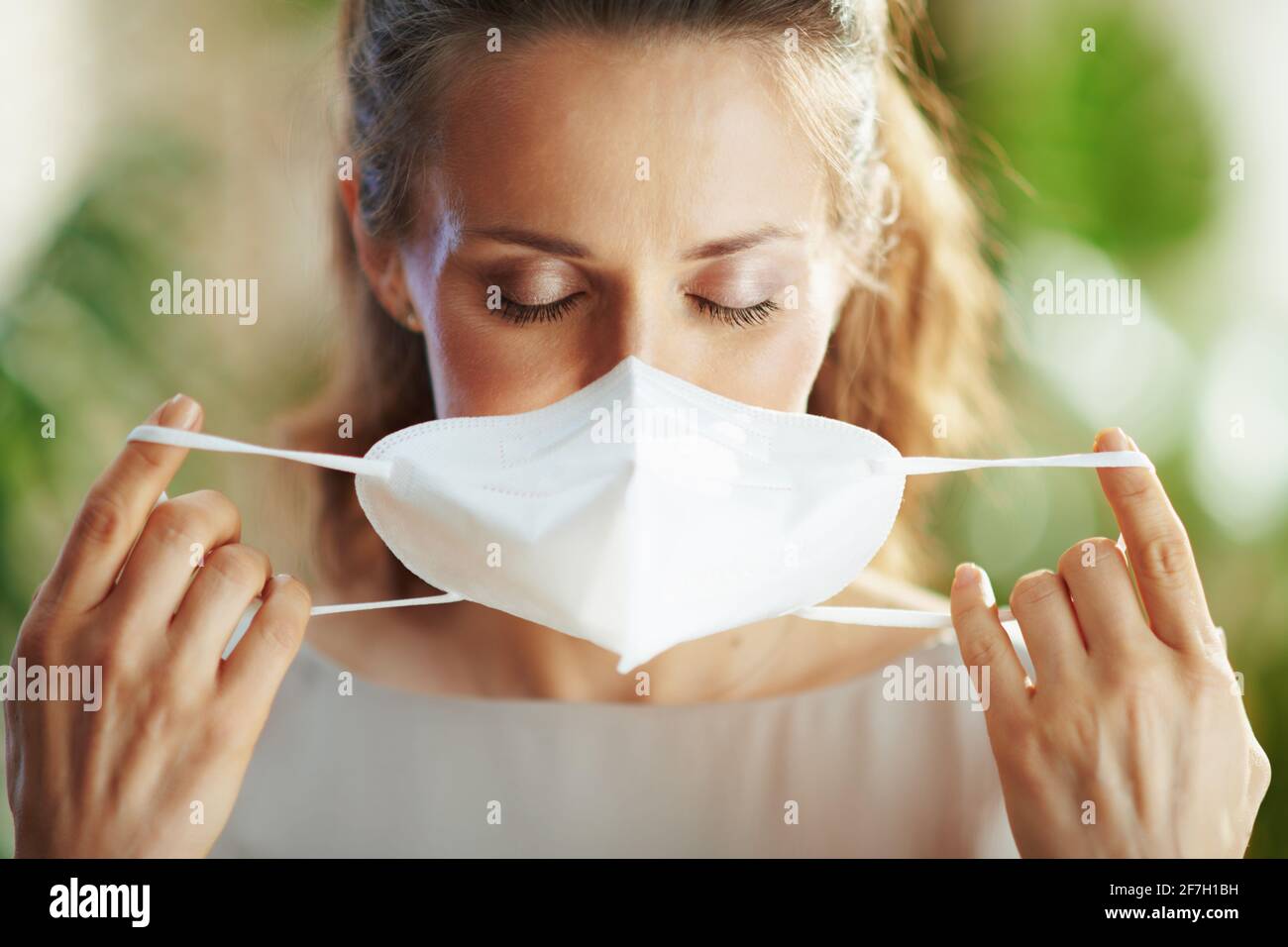 coronavirus pandemic. young female in grey blouse wearing ffp2 mask. Stock Photo