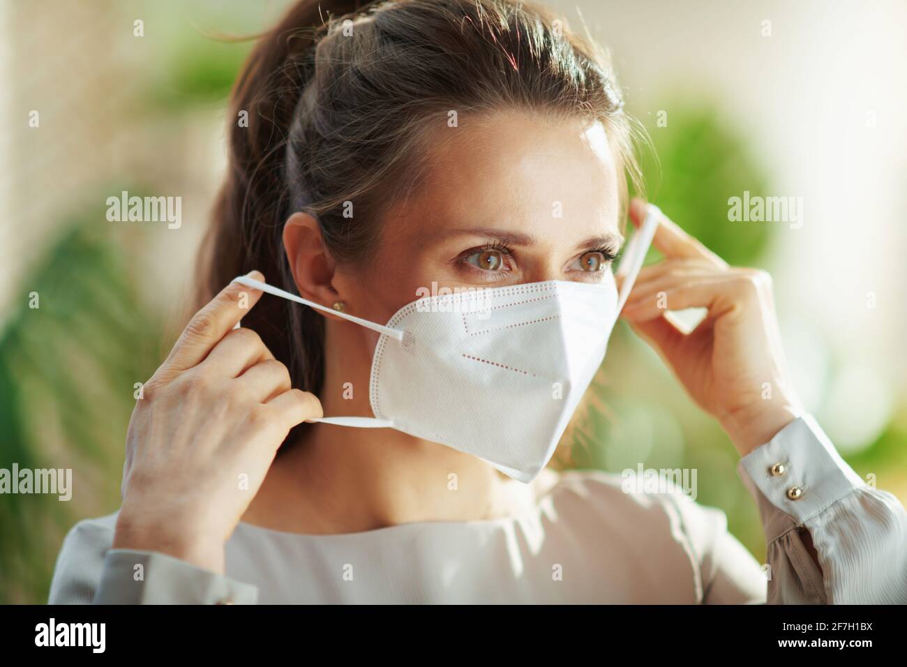 covid-19 pandemic. middle aged woman in grey blouse wearing ffp2 mask. Stock Photo