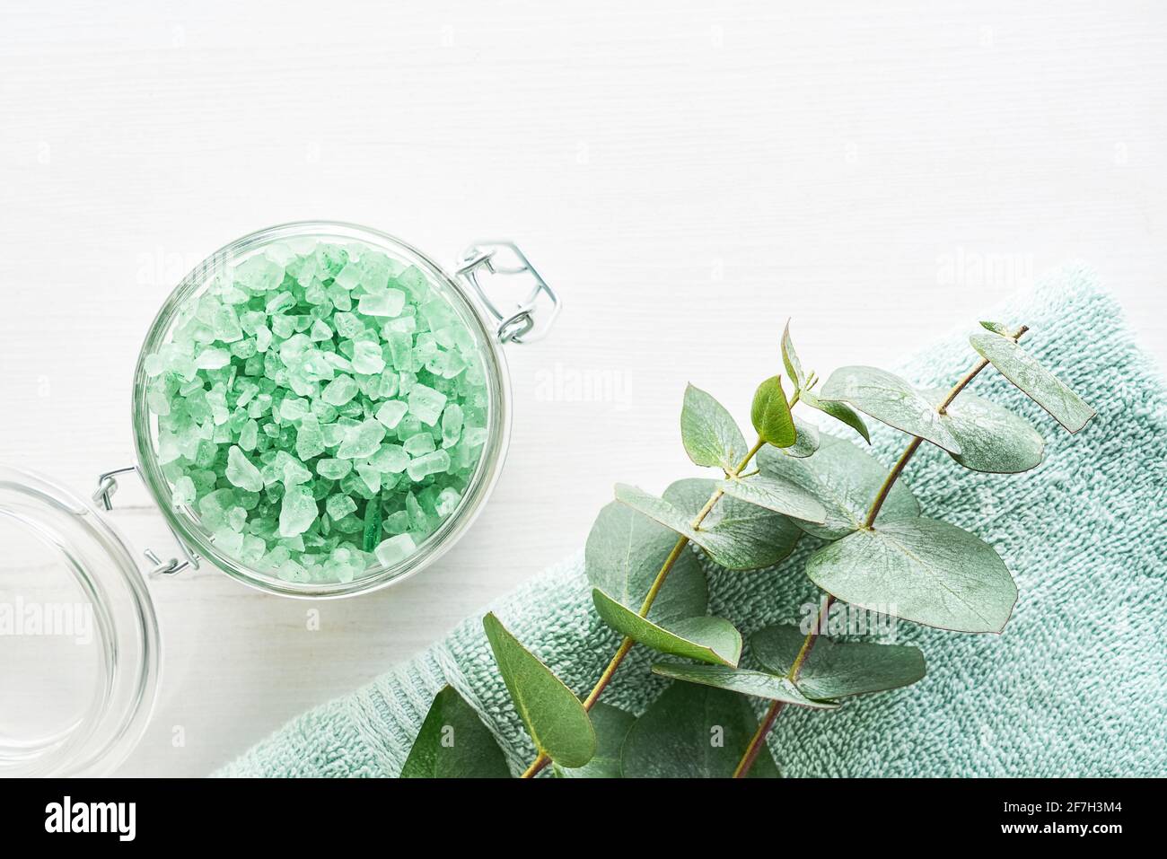 Towel, bath salt, and eucalyptus branch on white wooden background. SPA, Hygiene, wellness well-being, body care concept. Copy space Stock Photo