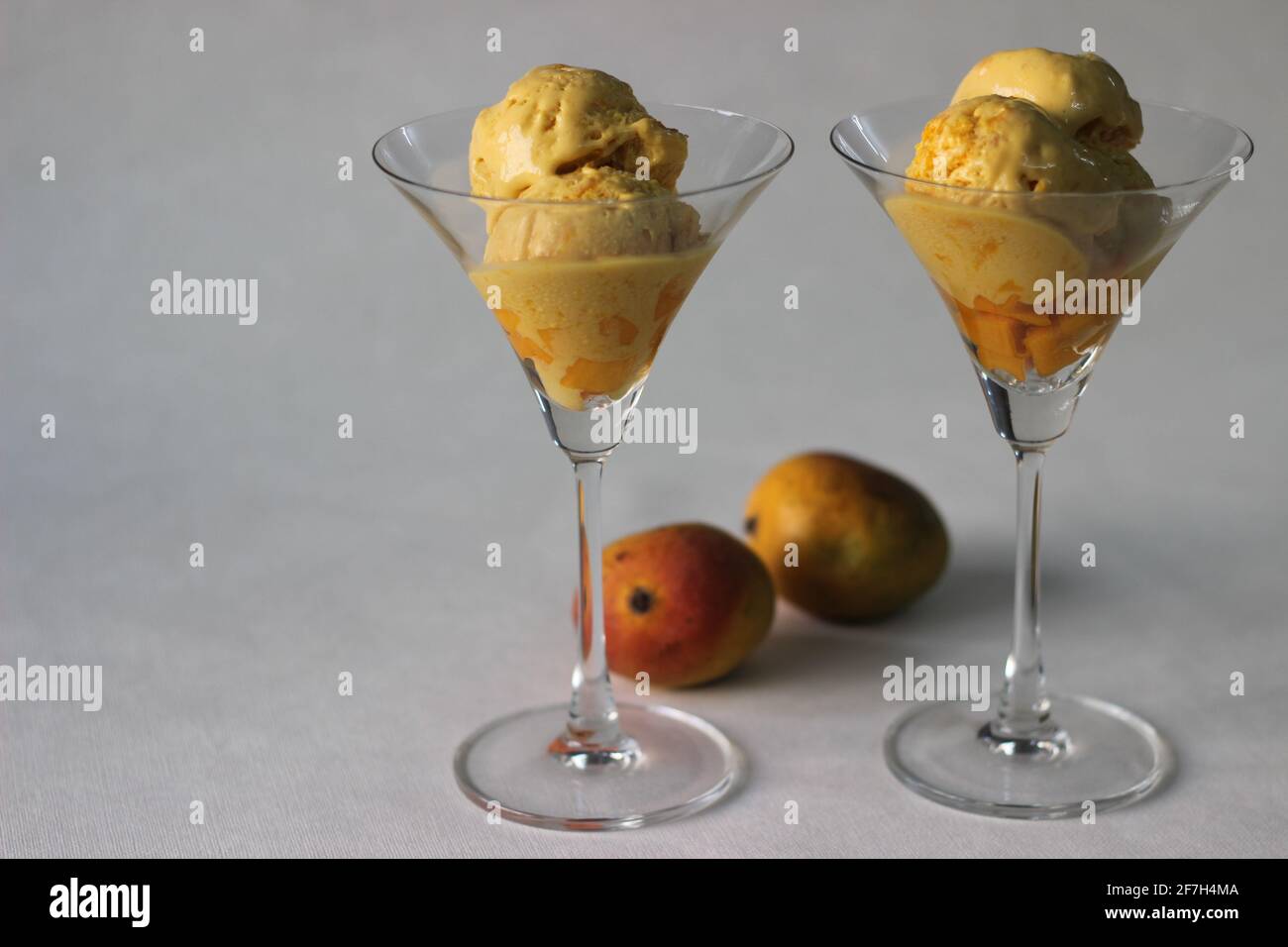 Scoops of Home made mango ice cream served in cocktail glass along with fresh cut Lalbagh mangoes. A treat in the summer heat. Stock Photo