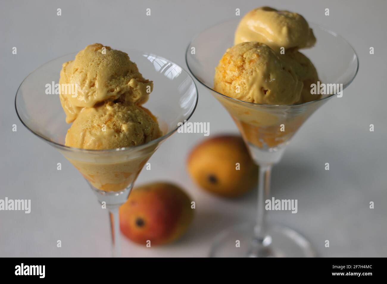 Scoops of Home made mango ice cream served in cocktail glass along with fresh cut Lalbagh mangoes. A treat in the summer heat. Stock Photo