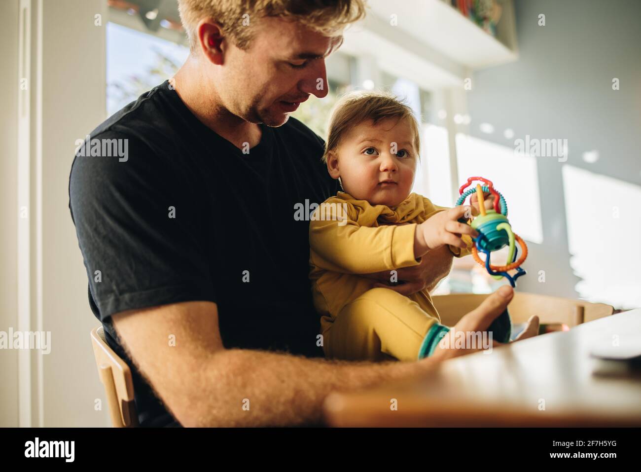Man spending quality time with his adorable child at home. Man on paternity leave at home taking care of his son. Stock Photo