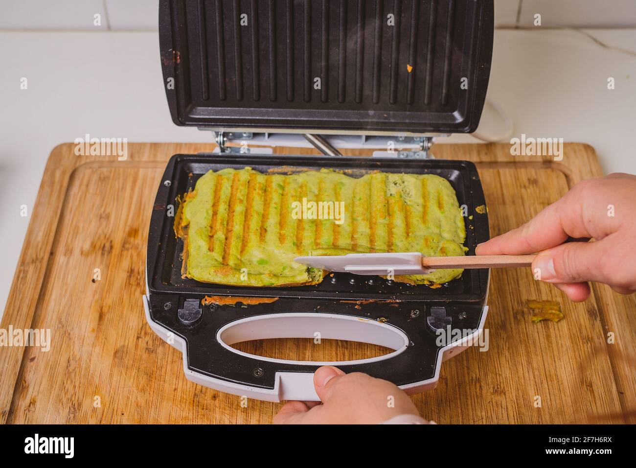 Woman making or preparing an avocado omlette in a toaster. Good delicious  LCHF style food made from avocado base, roasted in a grill toaster. Fresh  he Stock Photo - Alamy