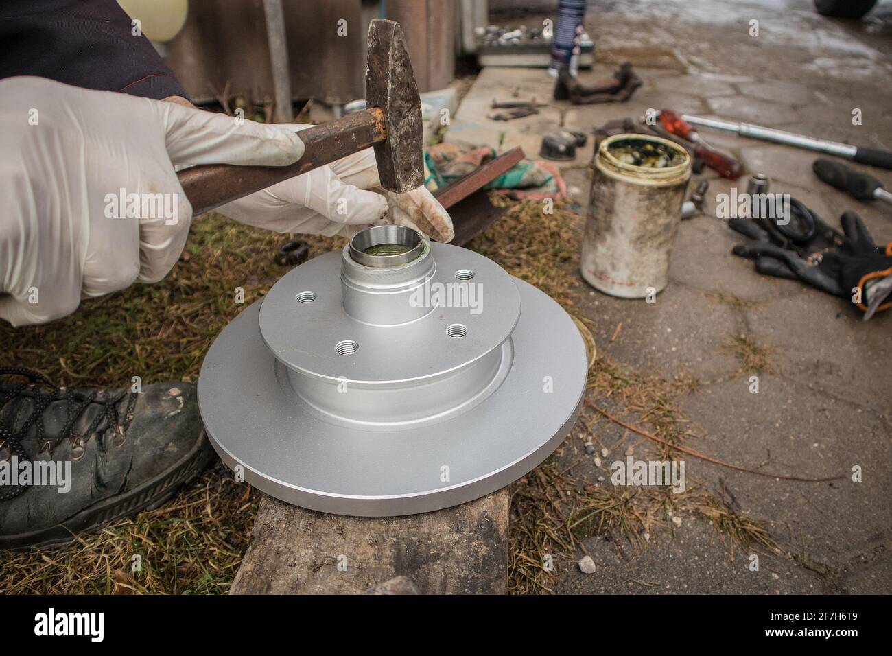 Hammering new bearing shell or race into car hub and brake disc using a