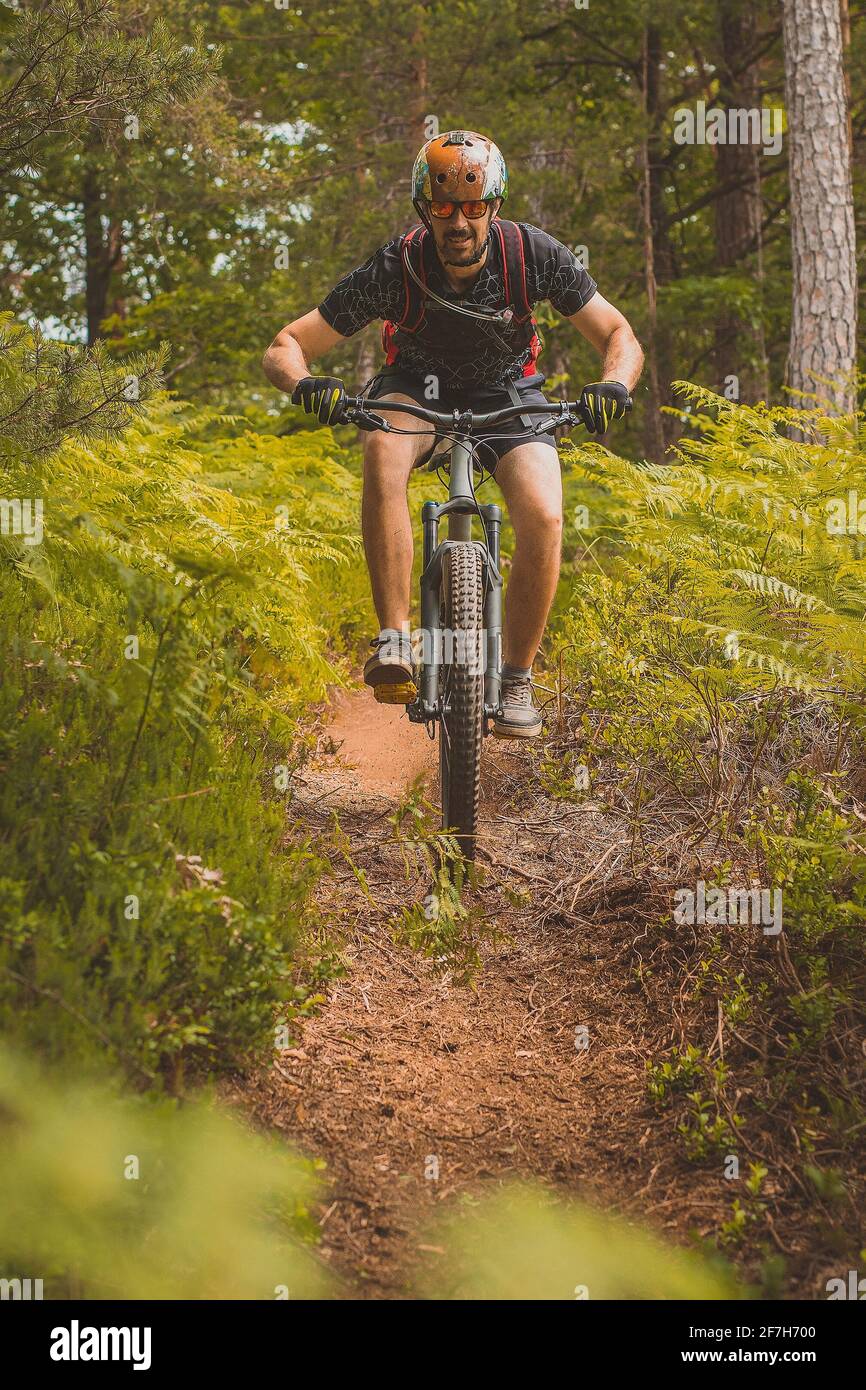 Man riding downhill with a mountain bike towards camera in a lush green  environment on a dirt single track course. Tall man going downhill with a  bike Stock Photo - Alamy