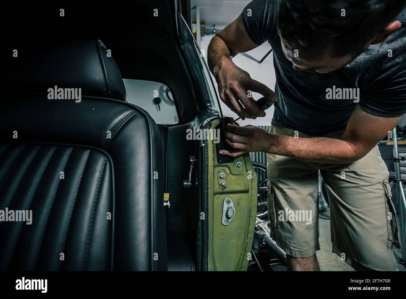 Young man removing interior trim panels from an old vintage car from