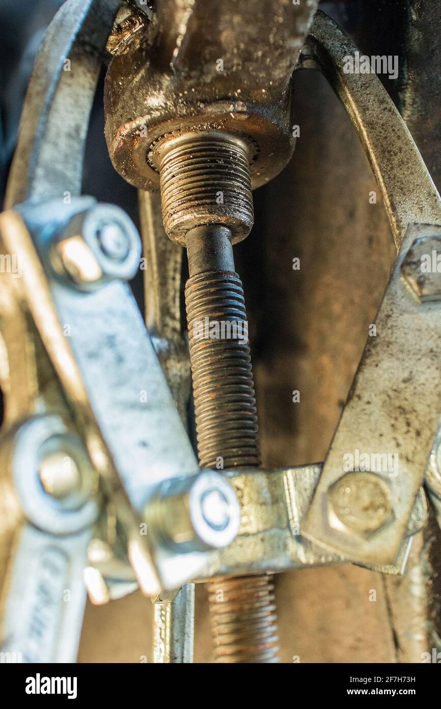 Three jaws puller in action while removing a metal arm from a splined