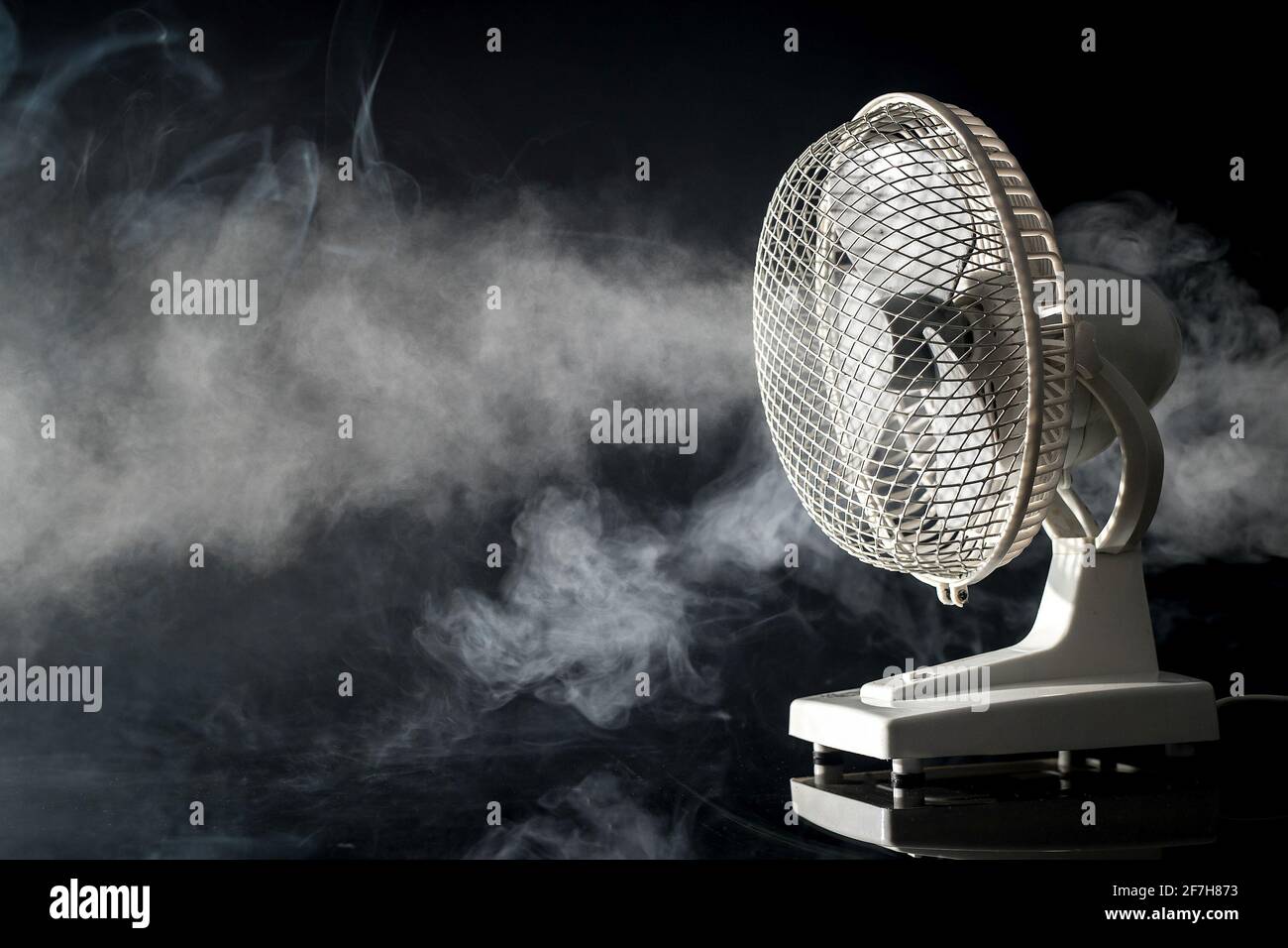 Side view of a white electric desktop fan on a black background and