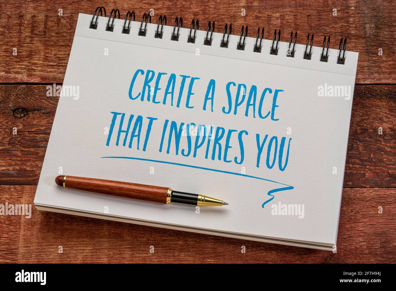 create a space that inspires you - inspirational writing in a spiral notebook with a stylish pen against weathered barn wood table, business and worki Stock Photo