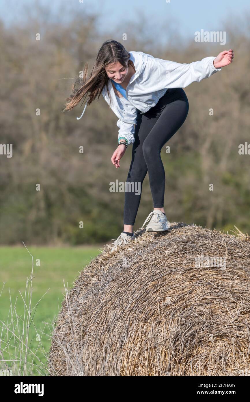 https://c8.alamy.com/comp/2F7HARY/latina-teenage-girl-in-black-leggings-top-and-jacket-posing-on-straw-bales-in-rural-setting-vertical-portrait-2F7HARY.jpg