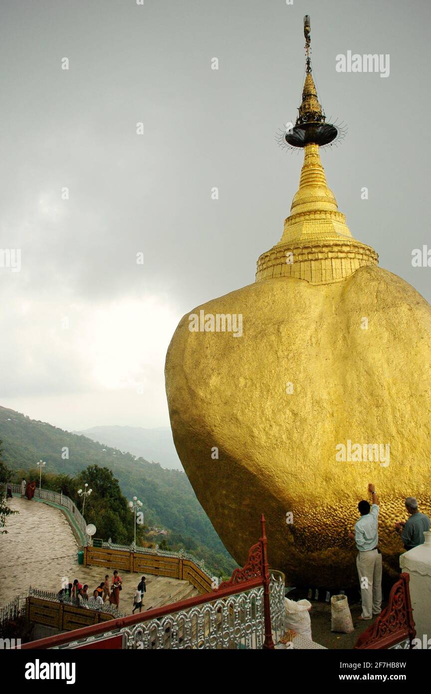 Men deposing gold on the Golden Rock, Kyaiktiyo Pagoda, Myanmar Stock Photo