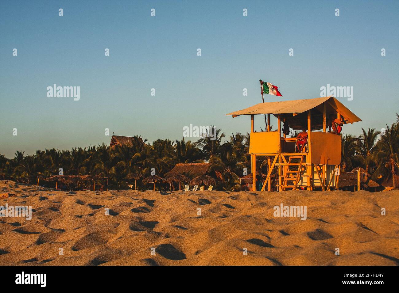 Typical beach in Puerto Escondido, Mexico, view towards the beach house, golden sand, trees and blue sky. Mexican lifeguards on duty. Stock Photo