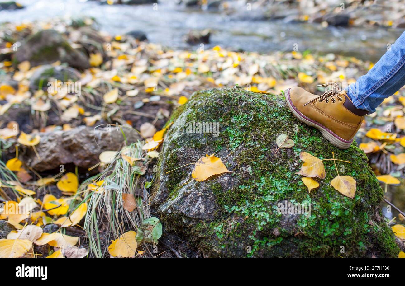 Child boy leather boot over mountain stream rock. Appropriate children shoes for nature Stock Photo