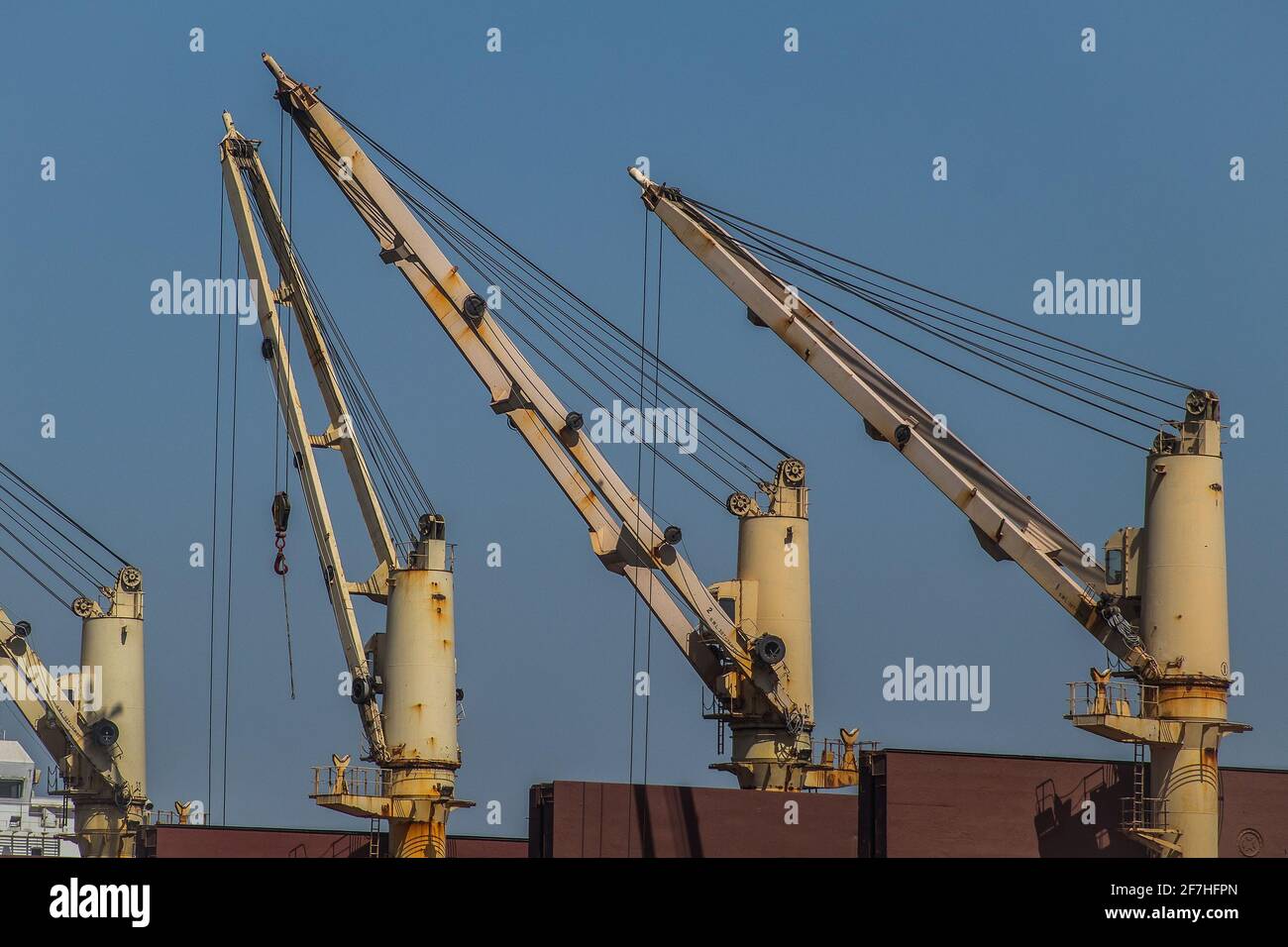 A set of white cranes or elevators mounted on a cargo ship. Stock Photo