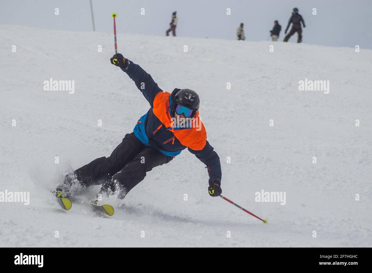A man agressively skiing towards the camera on a ski slope in cloudy conditions. Stock Photo