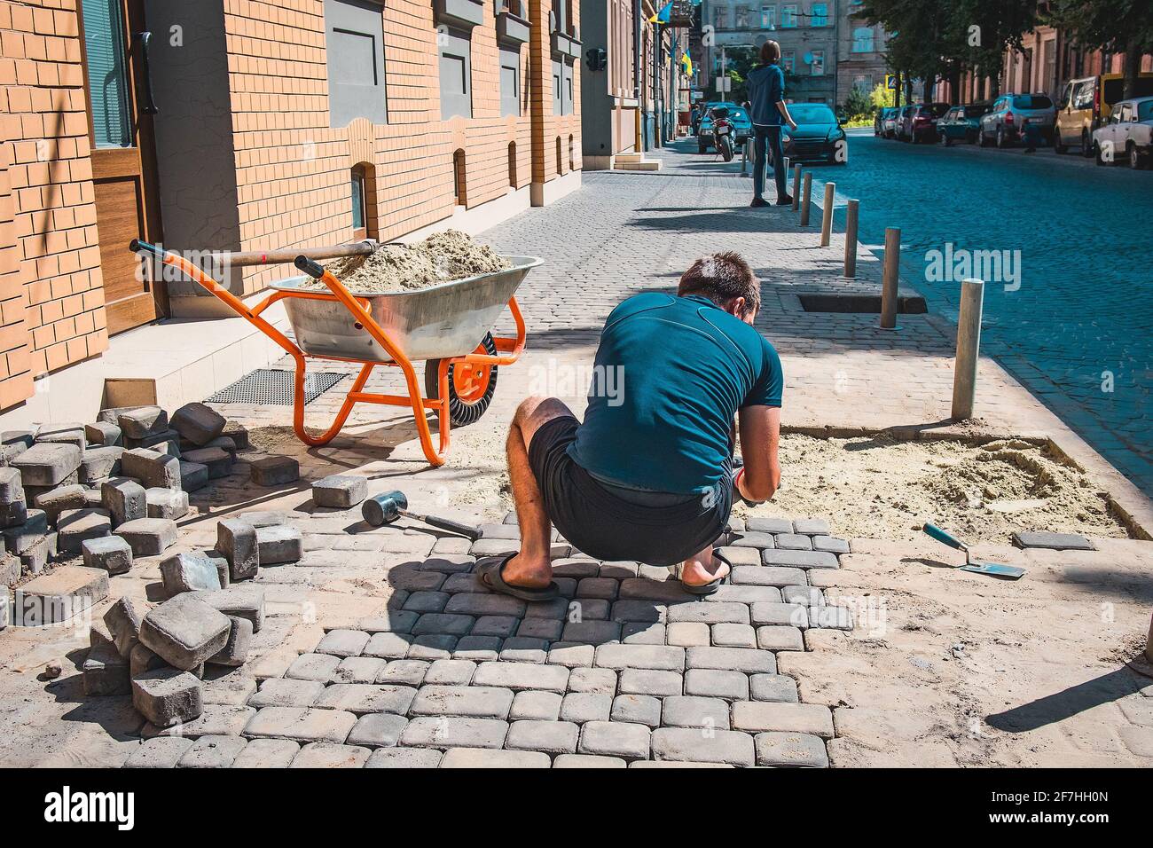 Rear view of a person putting tile or granite blocks on a pedestrian