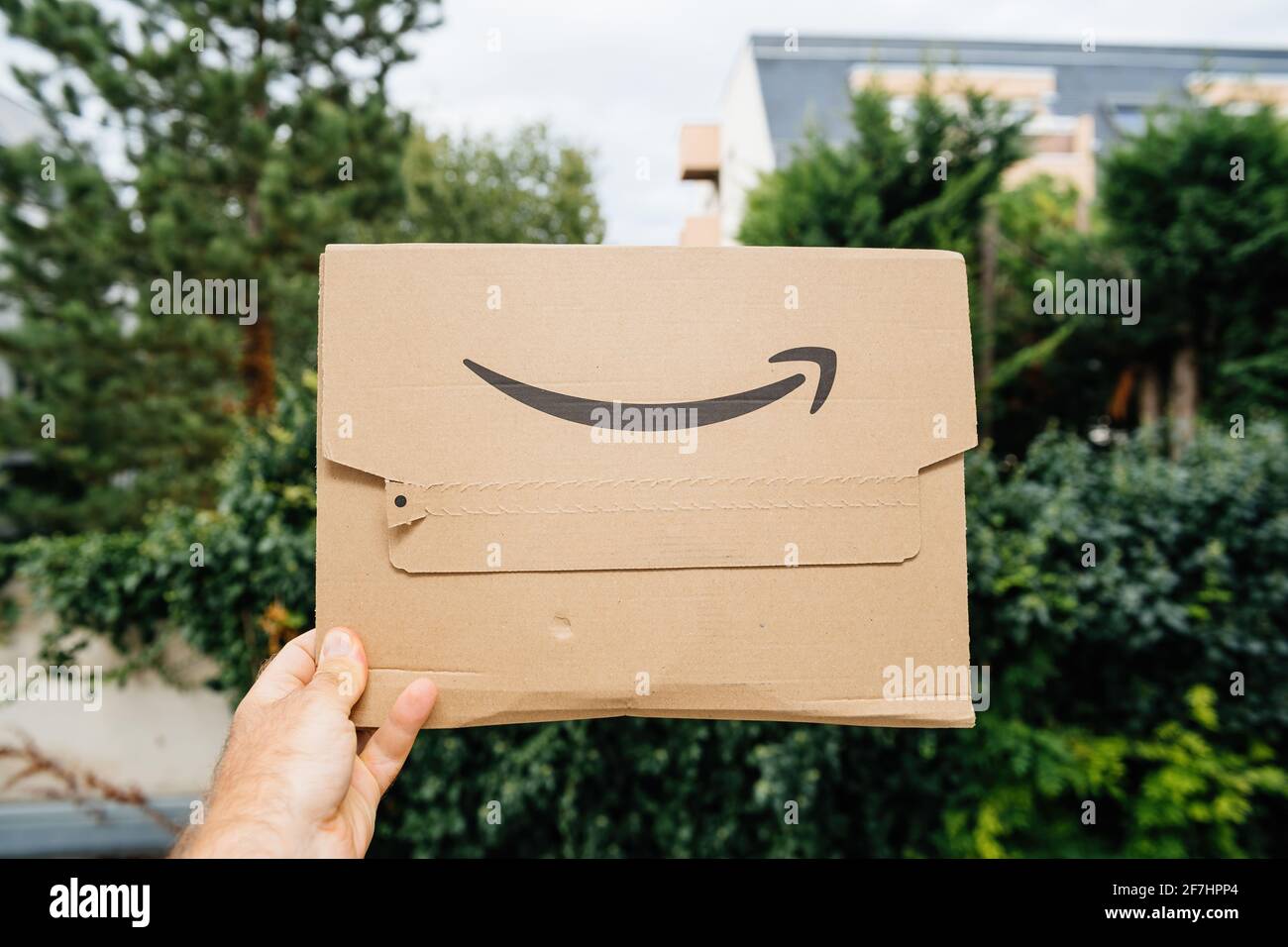 Pov male hand holding new package of Amazon Prime cardboard package Stock Photo