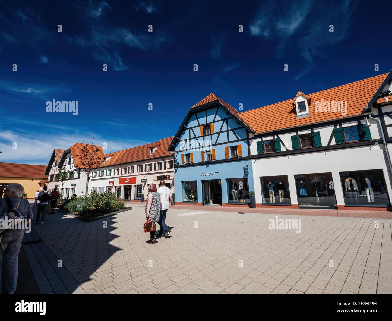 Rear view of unrecognizable couple walking in front of Gant fashion store  at Roppenheim The style Outlet Stock Photo - Alamy