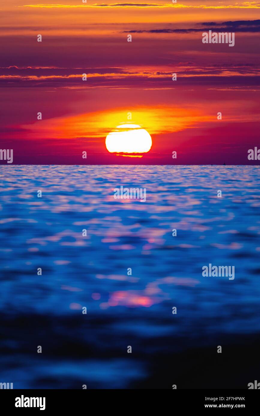 Colorful sunset with large bright sun under the sea surface. Sea sunset, ocean sunrise, seascape. Stock Photo