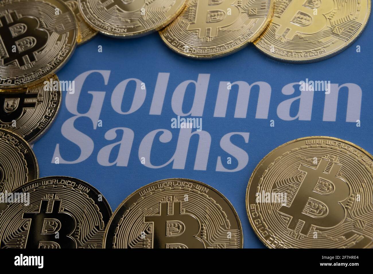 Bitcoin coins surround blurred Goldman Sachs logo seen on the paper. Concept. Selective focus. Stafford, United Kingdom, April 7, 2021. Stock Photo