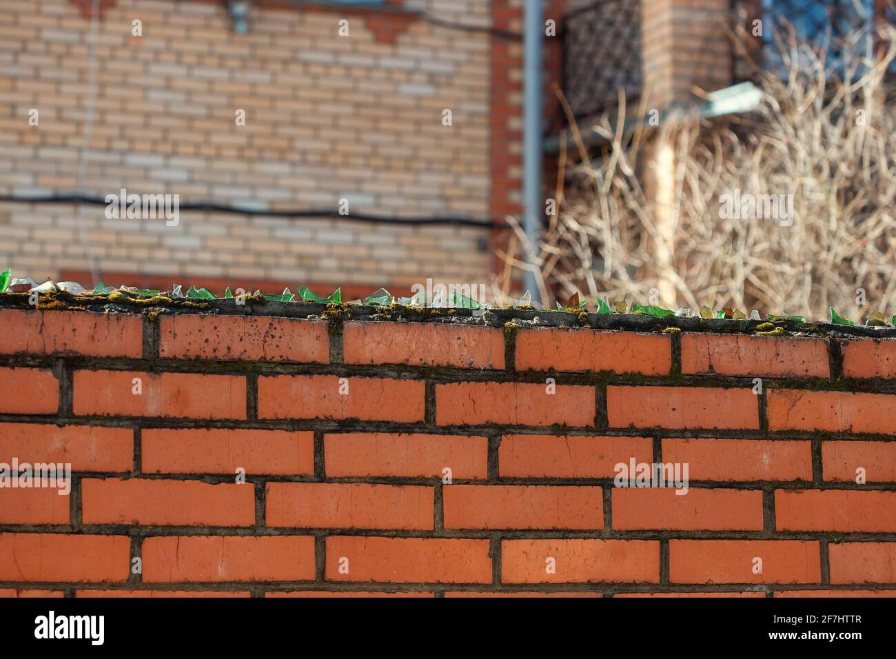 Broken glass glued to cement on top of a brick fence in a village. homemade security against robbers Stock Photo