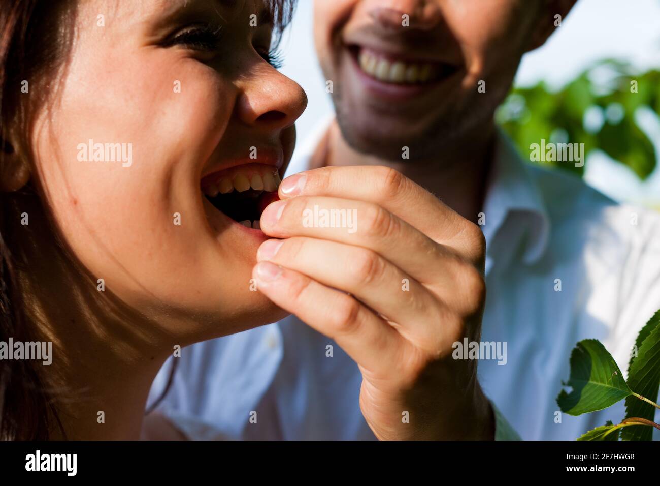 Happy couple eating cherries in summer in a garden Stock Photo