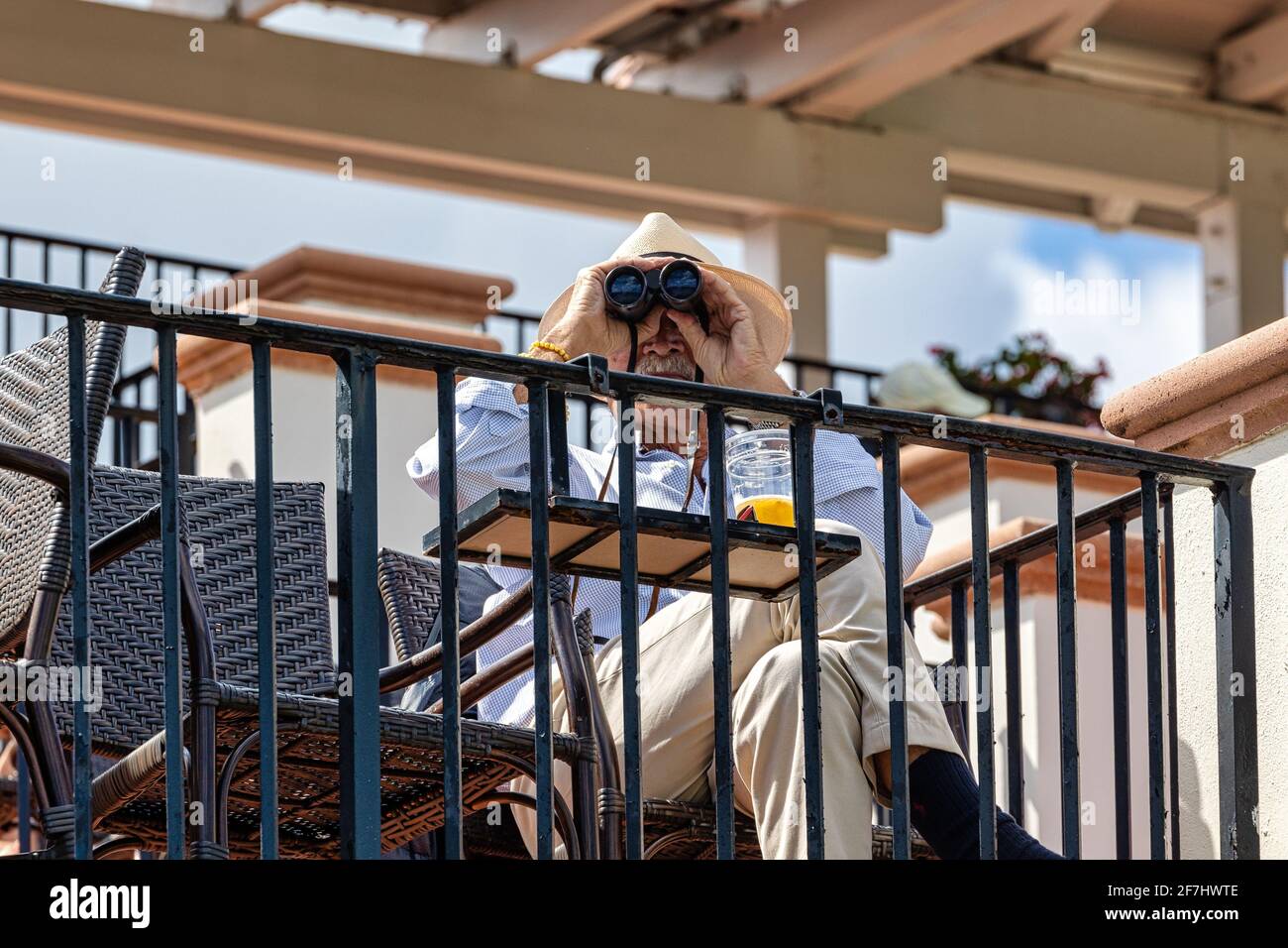WEST PALM BEACH, FL - MARCH 14, 2021: Man with straw hat watching an event with his binoculars. Stock Photo