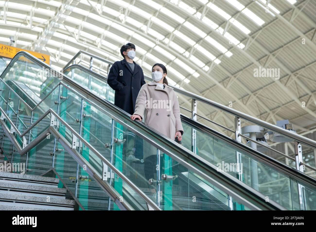 Asian man and woman with masks in escalator Stock Photo - Alamy