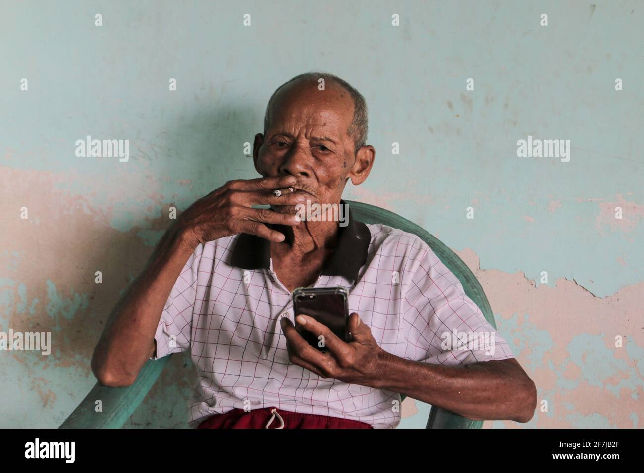 A portrait of Indonesian old grandpa calling in smartphone. Stock Photo