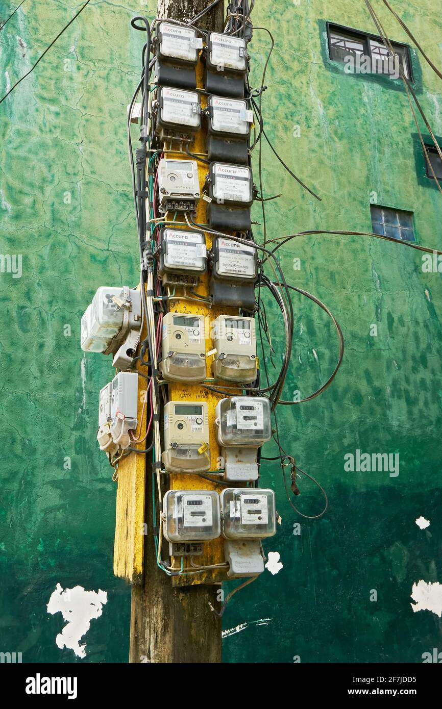 Many old dirty electric meters attached to a pole along the road, connecting electricity to residential household on Boracay Island, Philippines, Asia Stock Photo