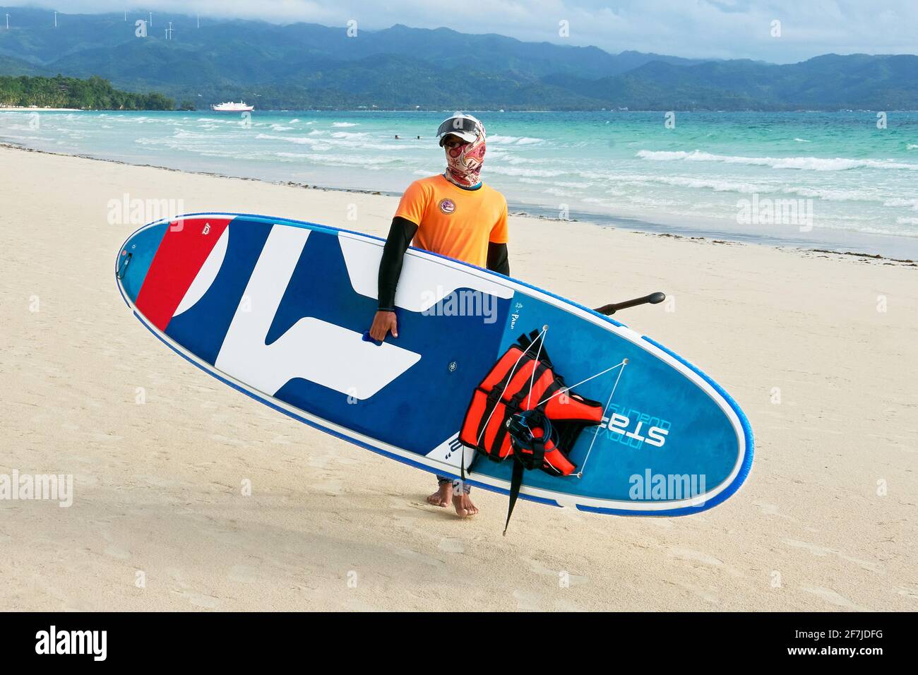Young instructor carrying a paddle boat at the clean and empty white Beach on Boracay Island, Aklan Province, Philippines, Asia, at lock down times Stock Photo