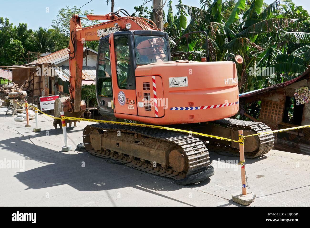 Red colored old Hitachi backhoe is parked on a newly cemented road on Boracay Island, Aklan Province, Philippines Stock Photo