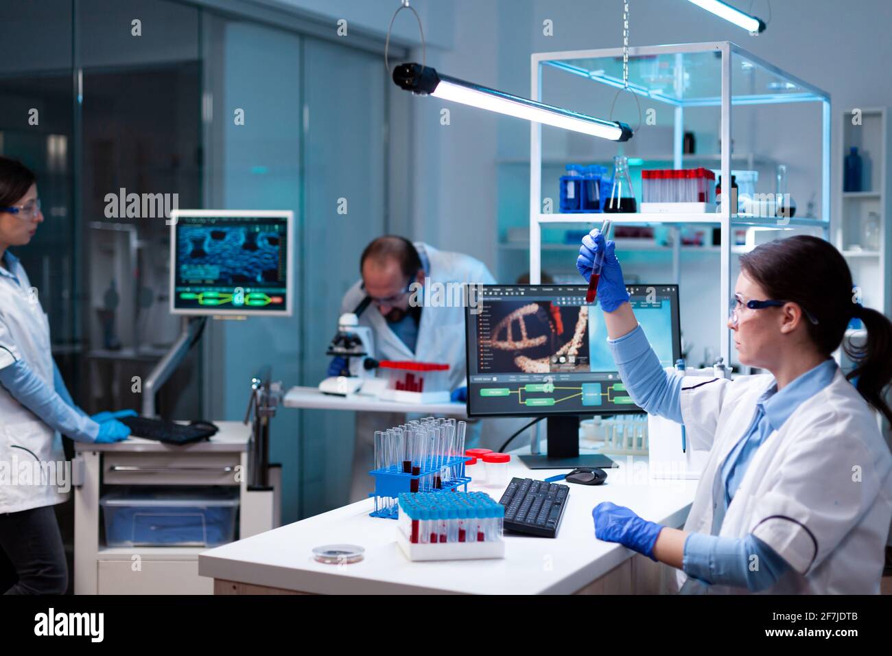 Scientist analyzing blood sample in test tube and team doing research ...