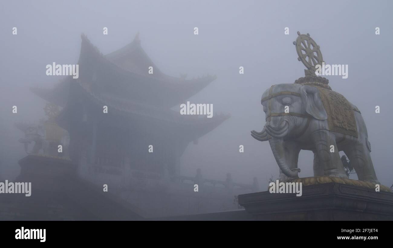 A buddhism temple with elephant statue almost hidden in heavy fog at Mount Emei,. Stock Photo