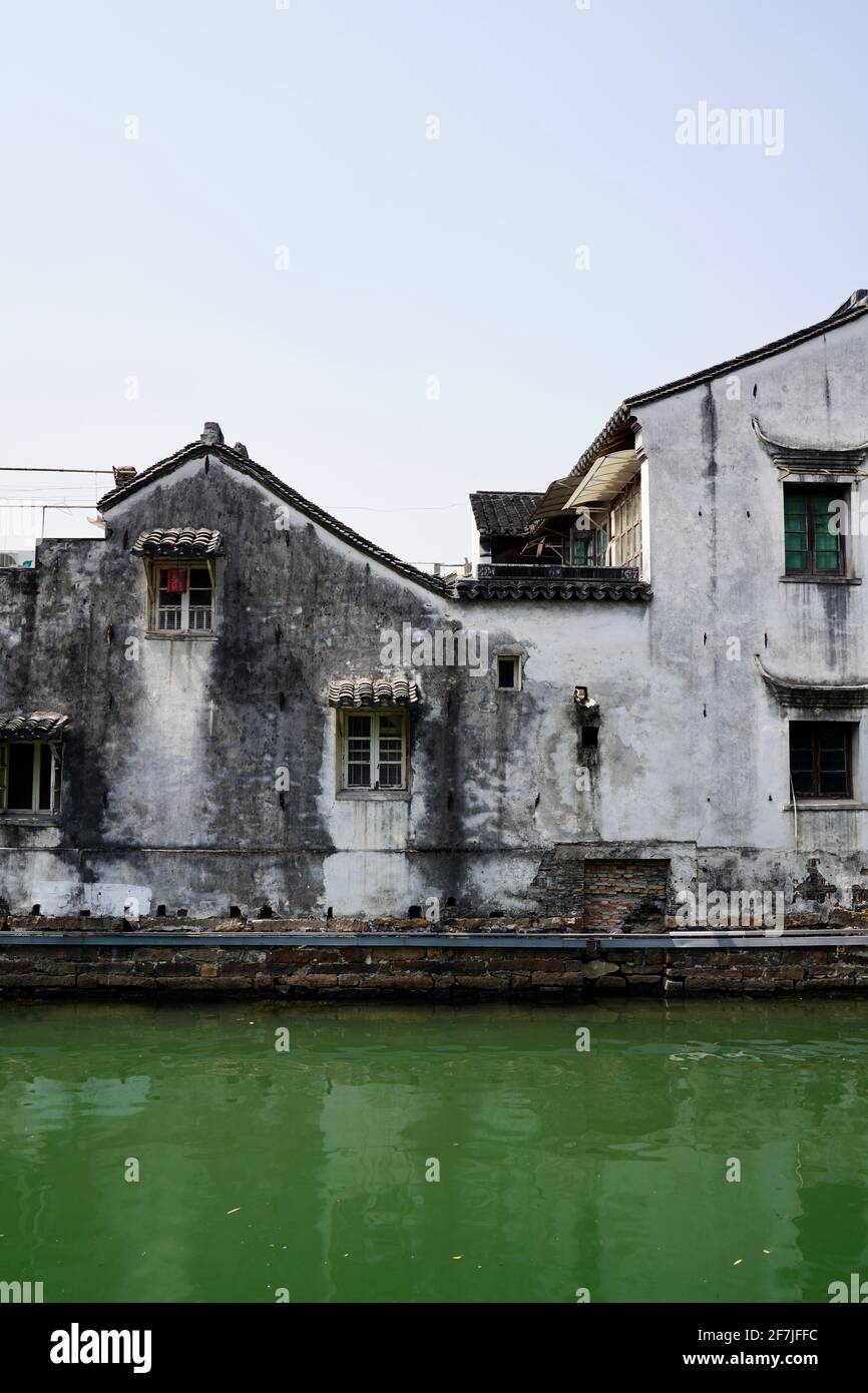 Old house with white wall and tile roof in Suzhou, also relfaction on green river. Stock Photo