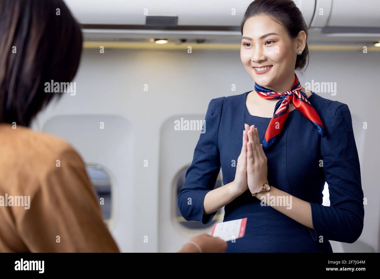 Cabin crew or Stewardess greeting passengers on airplane, Air hostess or stewardess service Stock Photo