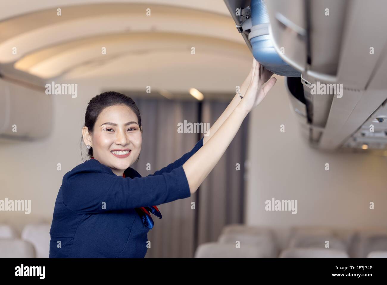 The stewardess helps the passengers to put their luggage in the cabin