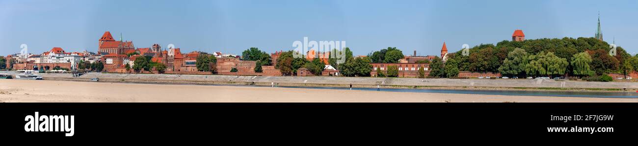 Wide panorama of Torun Old City in Poland with Medieval Gothic Cathedral of St. John. Vistula river. Extremely low water level with a great sandbank. Stock Photo