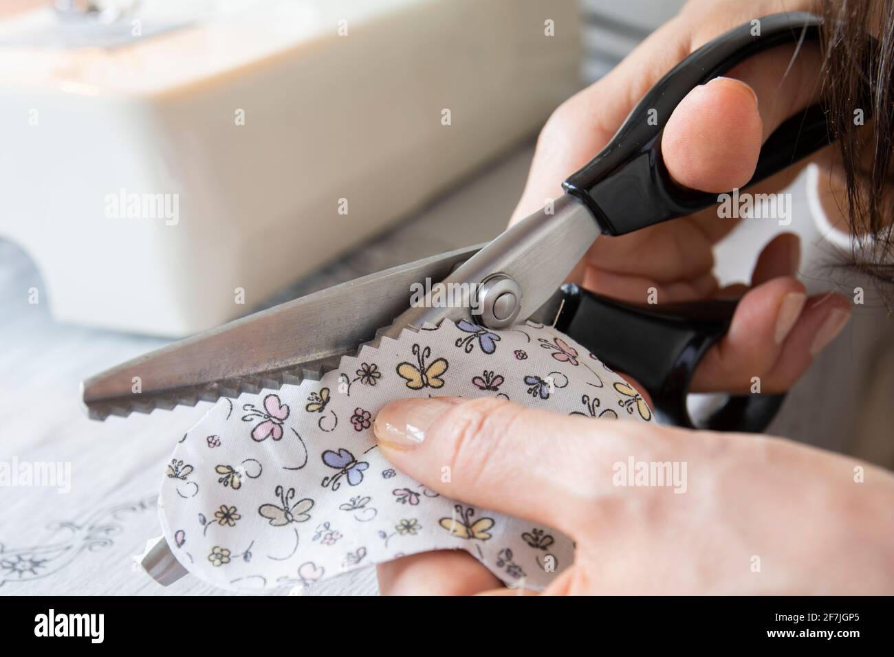 housewife is cutting fabric with serrated scissors Stock Photo