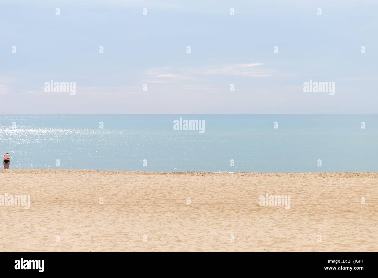 Minimalism photo. Beach, sky and sea line. One woman in sea cloth. Stock Photo